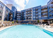 Thumbnail 4 of 53 - a large swimming pool with chaise lounge chairs and a building in the background