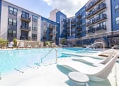 Thumbnail 5 of 53 - an outdoor swimming pool with chaise lounge chairs and an apartment building in the background