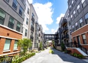 Thumbnail 19 of 53 - a walkway between two apartment buildings with a bridge in the background