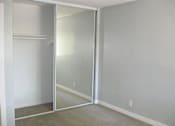 Thumbnail 5 of 16 - An empty bedroom with tan carpets and a sliding mirror doors to the closet
