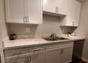 Thumbnail 7 of 16 - A kitchen with all white cabinets and chrome handles. The sink is in the middle.