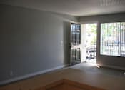 Thumbnail 10 of 16 - An empty living room looks out on an open front door with trees outside.