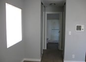 Thumbnail 13 of 16 - A large empty bedroom looks down the hallway lined with closets to the entryway into the bathroom