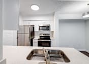 Thumbnail 6 of 10 - A kitchen with a sink, stove, and refrigerator.