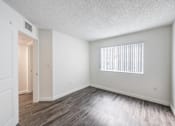 Thumbnail 8 of 10 - A room with a window and wooden flooring.