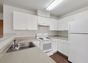 Thumbnail 71 of 74 - A white kitchen with a sink, stove, and refrigerator.