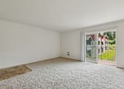Thumbnail 46 of 74 - A room with white walls and a carpeted floor with a doorway leading to a balcony.