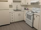 Thumbnail 22 of 24 - A white kitchen with a washing machine and dryer hanging from the ceiling at OTAVON APARTMENTS, Novato, CA