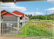 Thumbnail 32 of 74 - A view from a balcony overlooking a grassy area and a row of houses  at The Timbers by Vintage, 98223