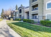 Thumbnail 3 of 12 - A residential building with a well-maintained lawn and a sidewalk at AGAVE APARTMENTS, Elk Grove, CA