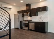 Thumbnail 17 of 41 - a kitchen with dark cabinets and stainless steel appliances at THE ANGELINO, Sacramento California