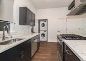 Thumbnail 25 of 41 - a kitchen with white countertops and black cabinets at THE ANGELINO, California, 95819