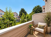Thumbnail 16 of 30 - A balcony with a chair and a table with a plant on it.