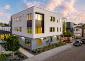 Thumbnail 58 of 81 - Apartments in Upper Land Park Sacramento CA - Market Club at The Mill - Buidling Exterior at Dusk with Streetview and White, Grey, and Black Design