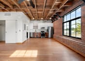 Thumbnail 26 of 81 - a living room with a large window and a kitchen with a wood floor