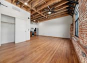 Thumbnail 35 of 81 - an empty living room with wood floors and a brick wall