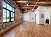 Thumbnail 36 of 81 - an empty room with wood floors and a brick wall and large windows