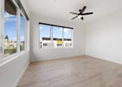 Thumbnail 20 of 81 - Studio Apartments in Upper Land Park Sacramento CA - Market Club at The Mill - Unfurnished Living Room Space with Large Windows, Plank-Style Flooring, and Ceiling Fan