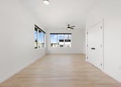Thumbnail 11 of 81 - Pet-Friendly Apartments In Upper Land Park, Sacramento - Market Club At The Mill - Empty Living Room With Windows, Wood-Style Flooring, Closet, And Ceiling Fan