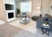 Thumbnail 1 of 10 - A living room with a grey couch, a white fireplace, and a television on the wall at Laguna, CA, 95823