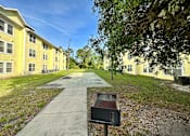 Thumbnail 5 of 21 - a walkway between two yellow buildings with a grill in the middle of the walkway at SUMMERBREEZE & SUMMERSET, ST. AUGUSTINE, FL