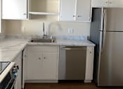 Thumbnail 9 of 19 - A kitchen with white cabinets and a wooden wall.at Via Casitas, California
