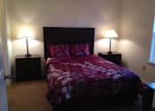 Thumbnail 18 of 28 - A bed with a purple comforter and two matching lamps.