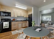 Thumbnail 18 of 20 - A modern kitchen with a dining table set for two at Lake Washington Apartments, Seattle