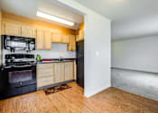 Thumbnail 8 of 20 - A kitchen with black appliances and wooden cabinets.at Lake Washington Apartments, Washington