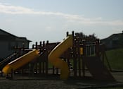 Thumbnail 14 of 28 - A yellow slide in a playground with a wooden structure.