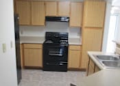 Thumbnail 3 of 28 - A kitchen with a black stove and wooden cabinets.