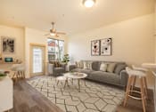 Thumbnail 2 of 29 - A living room with a grey couch and a black and white rug. at Fairview Village Apartments, Fairview, OR, 97024