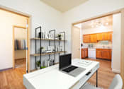 Thumbnail 21 of 34 - A laptop is on a desk in a room with a kitchen in the background. at Fairview Village Homes, Oregon