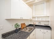 Thumbnail 21 of 36 - A kitchen with white cabinets and a granite countertop.at Palladian Apartments, Portland Oregon ? 
