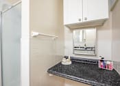 Thumbnail 25 of 36 - A bathroom with a black granite countertop and white cabinets.at Palladian Apartments, Oregon ? 