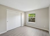 Thumbnail 13 of 39 - A room with a white door and a window showing greenery outside.