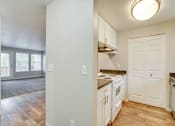 Thumbnail 37 of 39 - A kitchen with white cabinets and a wooden floor.