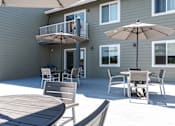 Thumbnail 12 of 20 - A patio with a table and chairs and an umbrella.