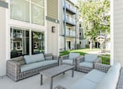 Thumbnail 3 of 20 - A patio with a grey sofa, two chairs and a table.