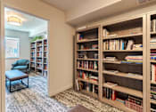 Thumbnail 16 of 20 - A room with a bookshelf filled with books and a chair.