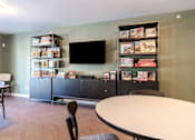 Thumbnail 17 of 20 - A room with a table, chairs, and a bookshelf filled with books.