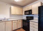 Thumbnail 20 of 20 - A kitchen with black appliances and wooden cabinets.