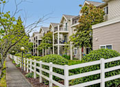 Thumbnail 3 of 26 - A white picket fence separates a sidewalk from a row of houses at Vintage at Burien,Burien,WA,98168