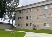 Thumbnail 2 of 5 - the side of a building with grass and a sidewalk