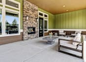 Thumbnail 6 of 18 - A modern outdoor living space with a stone fireplace and seating area at View by Vintage Apartments, Bonney Lake
