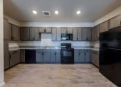 Thumbnail 3 of 14 - an empty kitchen with black appliances and wooden cabinets at Springview by Vintage, NV, 89512
