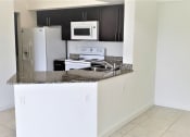 Thumbnail 10 of 14 - Mirabella Apartments kitchen area with white appliances and bar top for seating at Mirabella Apartments, Florida