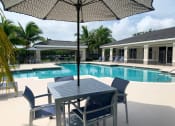 Thumbnail 4 of 27 - Resort style pool and umbrella with chairs at Tuscany Place Apartments, Homestead 