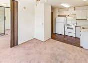 Thumbnail 18 of 27 - an empty living room with a kitchen with white appliances