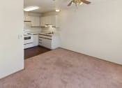 Thumbnail 19 of 27 - an empty living room and kitchen with white appliances and carpeting